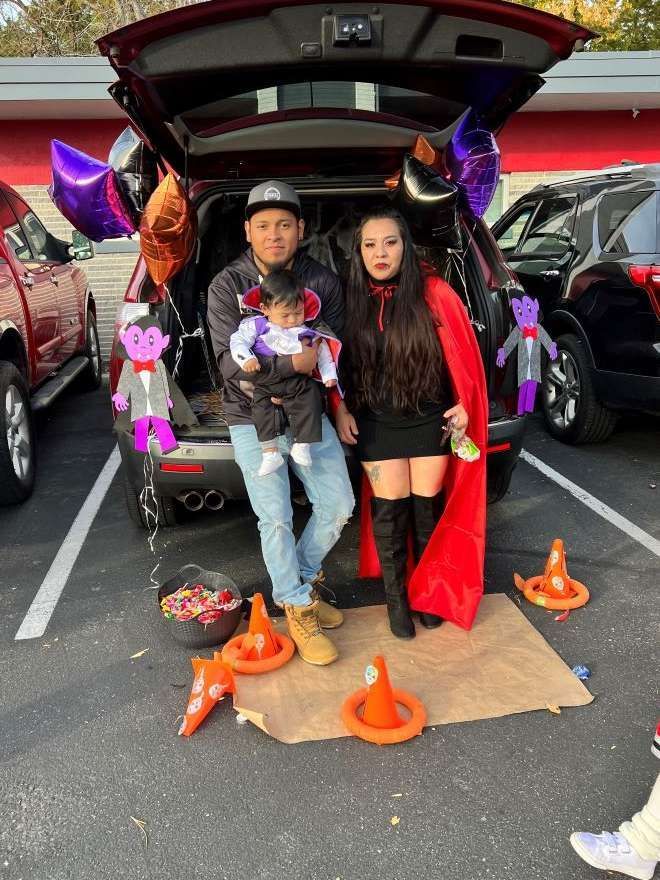 A family is posing for a picture in the trunk of a car.