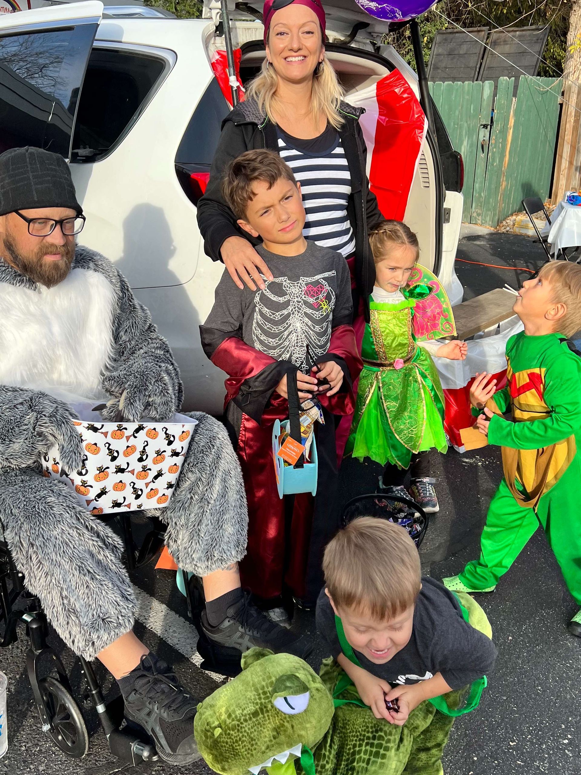 A group of people in costumes are posing for a picture in front of a car.