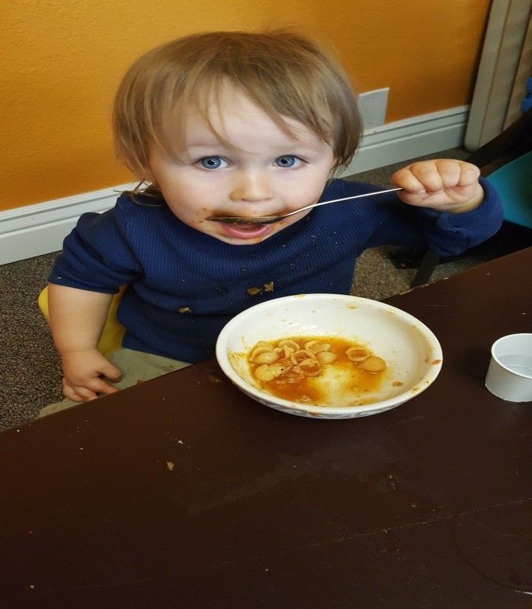 A little boy is eating a bowl of food with a spoon