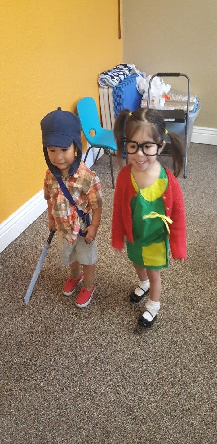 A boy and a girl in costumes are standing next to each other on the floor.