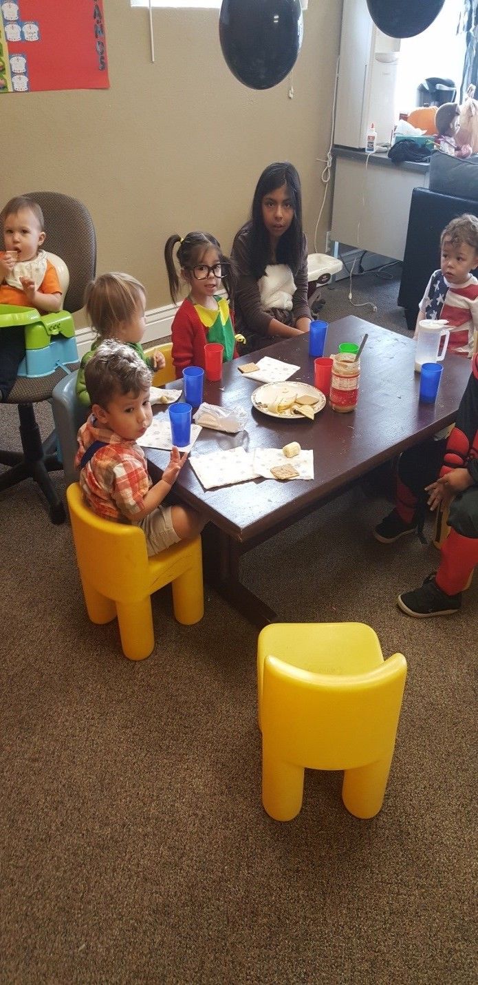 A group of children are sitting around a table eating food.