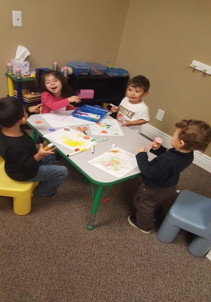 A group of children are sitting around a table in a room.