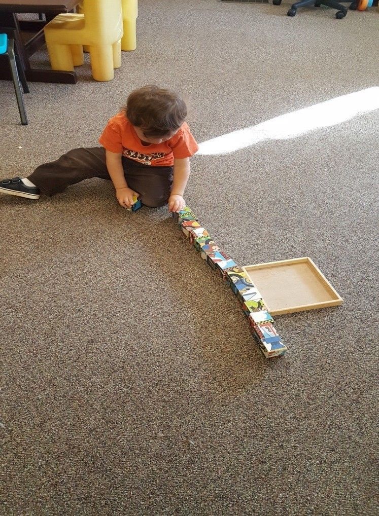 A young boy is playing with a toy train on the floor.