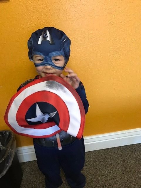 A little boy dressed as captain america holding a shield