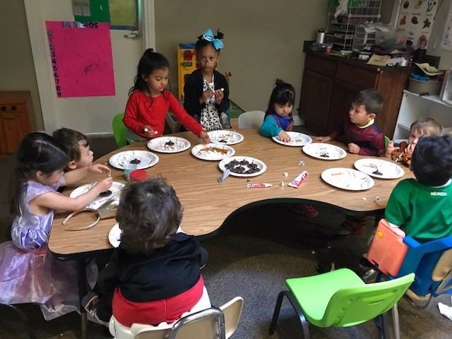A group of children are sitting around a table with plates of food