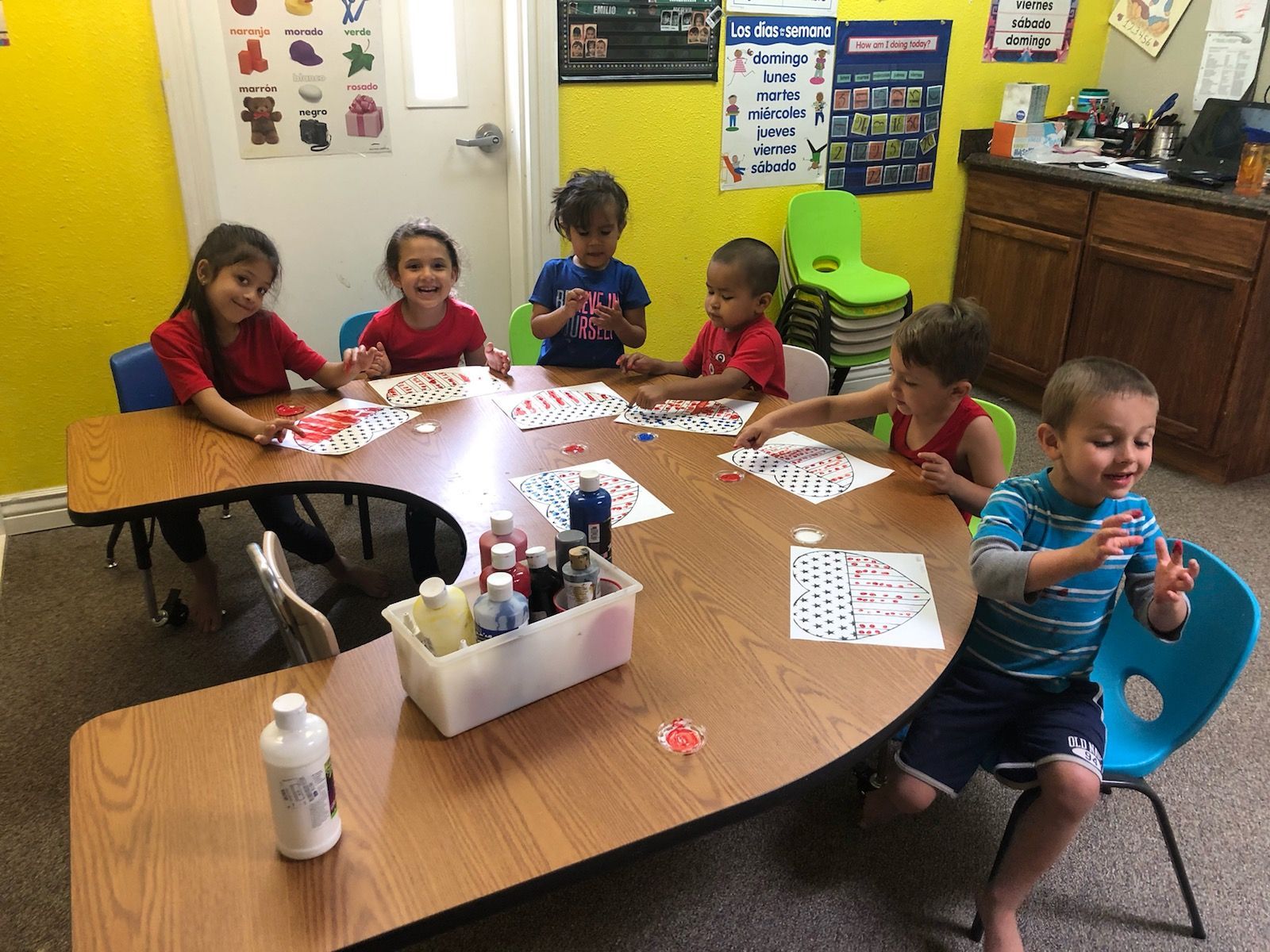 A group of children are sitting at a table in a classroom.