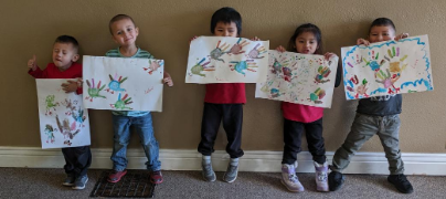 A group of children are holding up their handprints on paper.