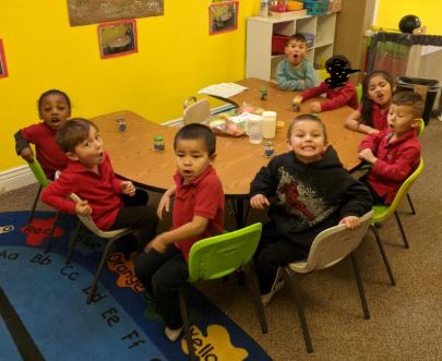 A group of children are sitting around a table in a classroom