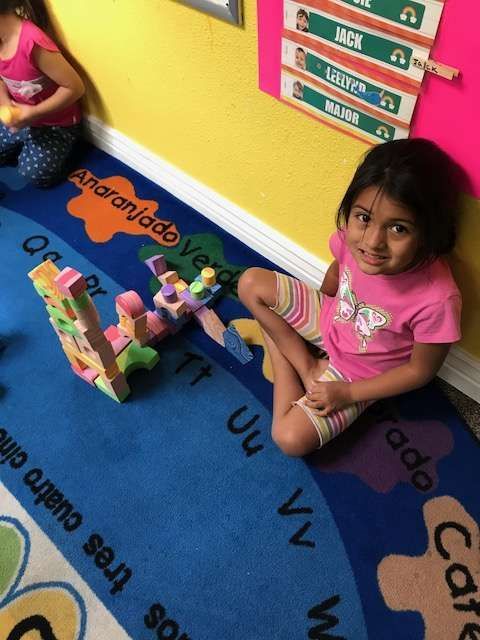 A little girl sits on a rug with the letters u and v on it