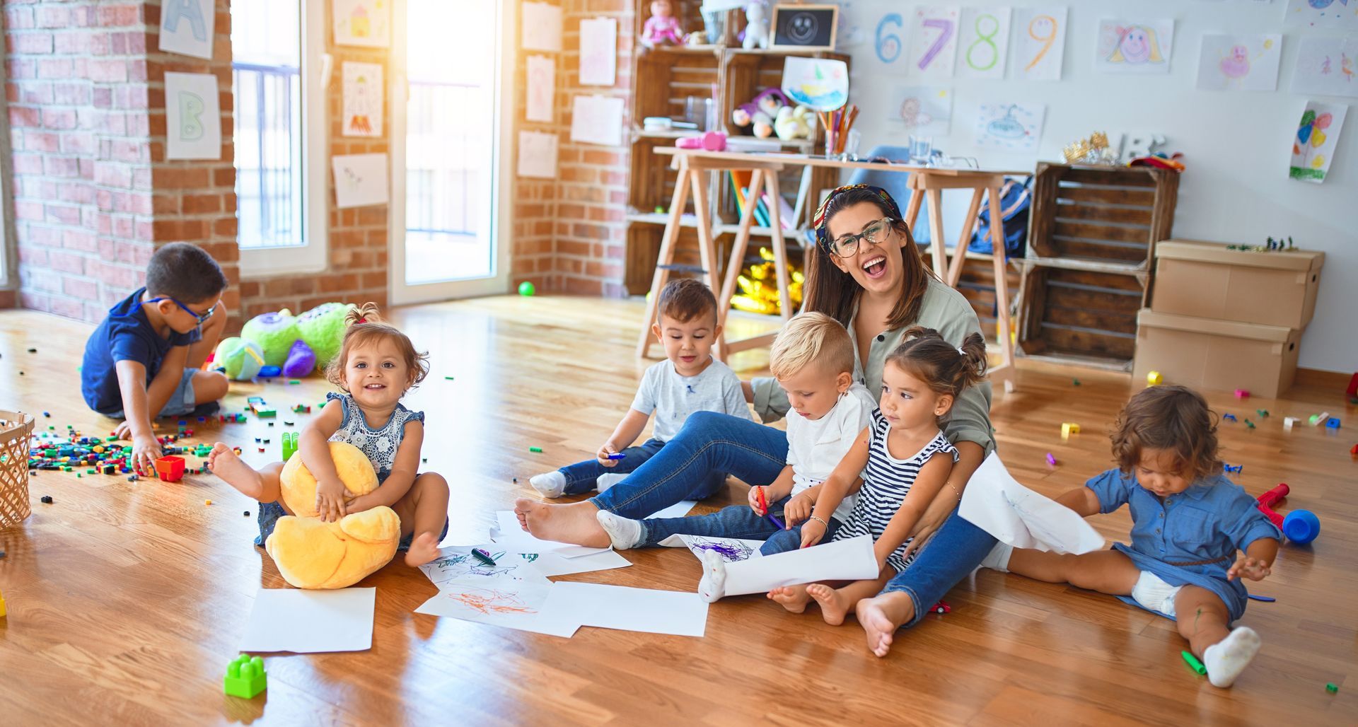 A Group of Children and a Teacher Are Sitting on the Floor in a Classroom