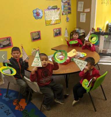 A group of children are sitting around a table with plates in their hands