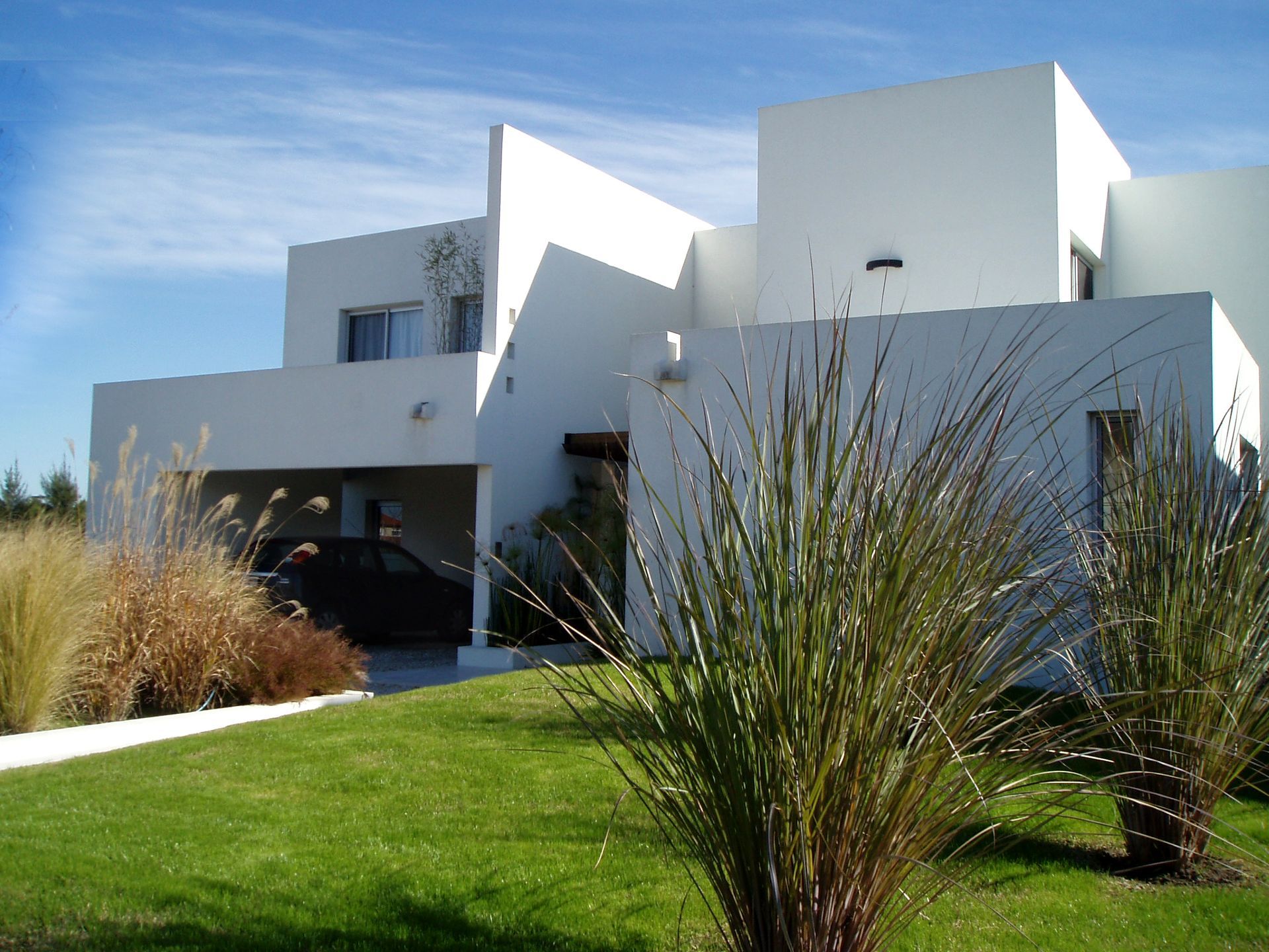 Casa blanca moderna con césped y plantas.