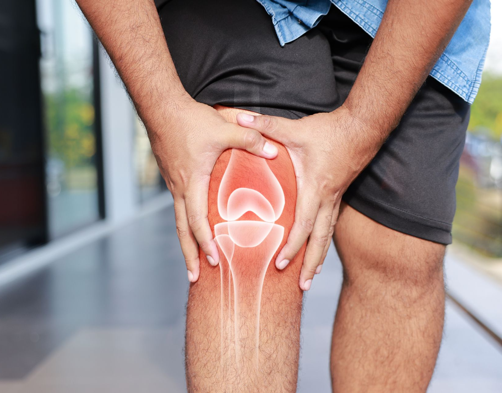 Person clutching a glowing red knee, indicating joint pain or injury.