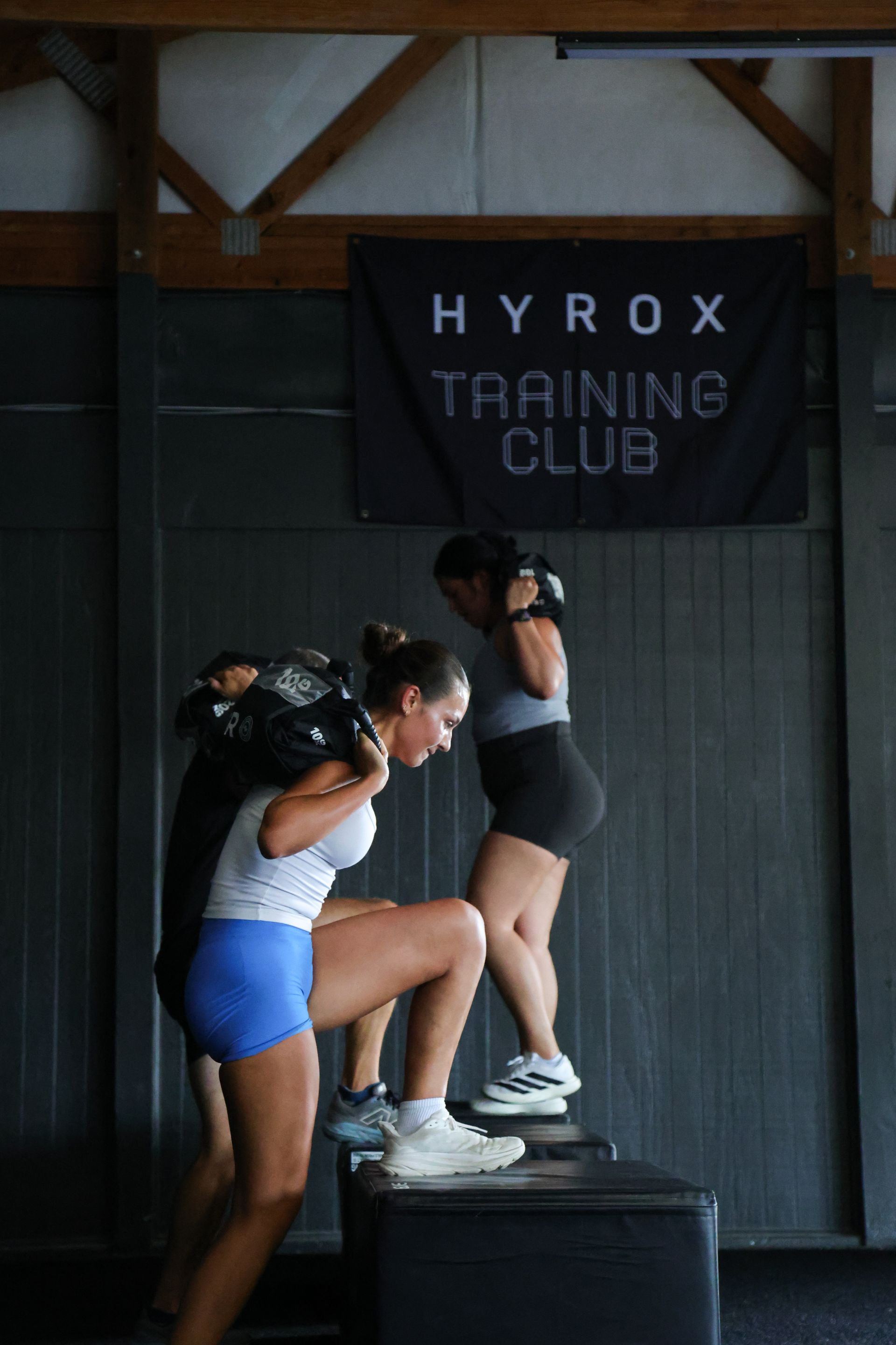 A woman is doing squats on a bench in a gym.