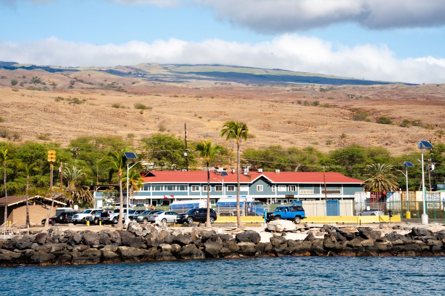 A large building with a red roof is sitting next to a body of water.