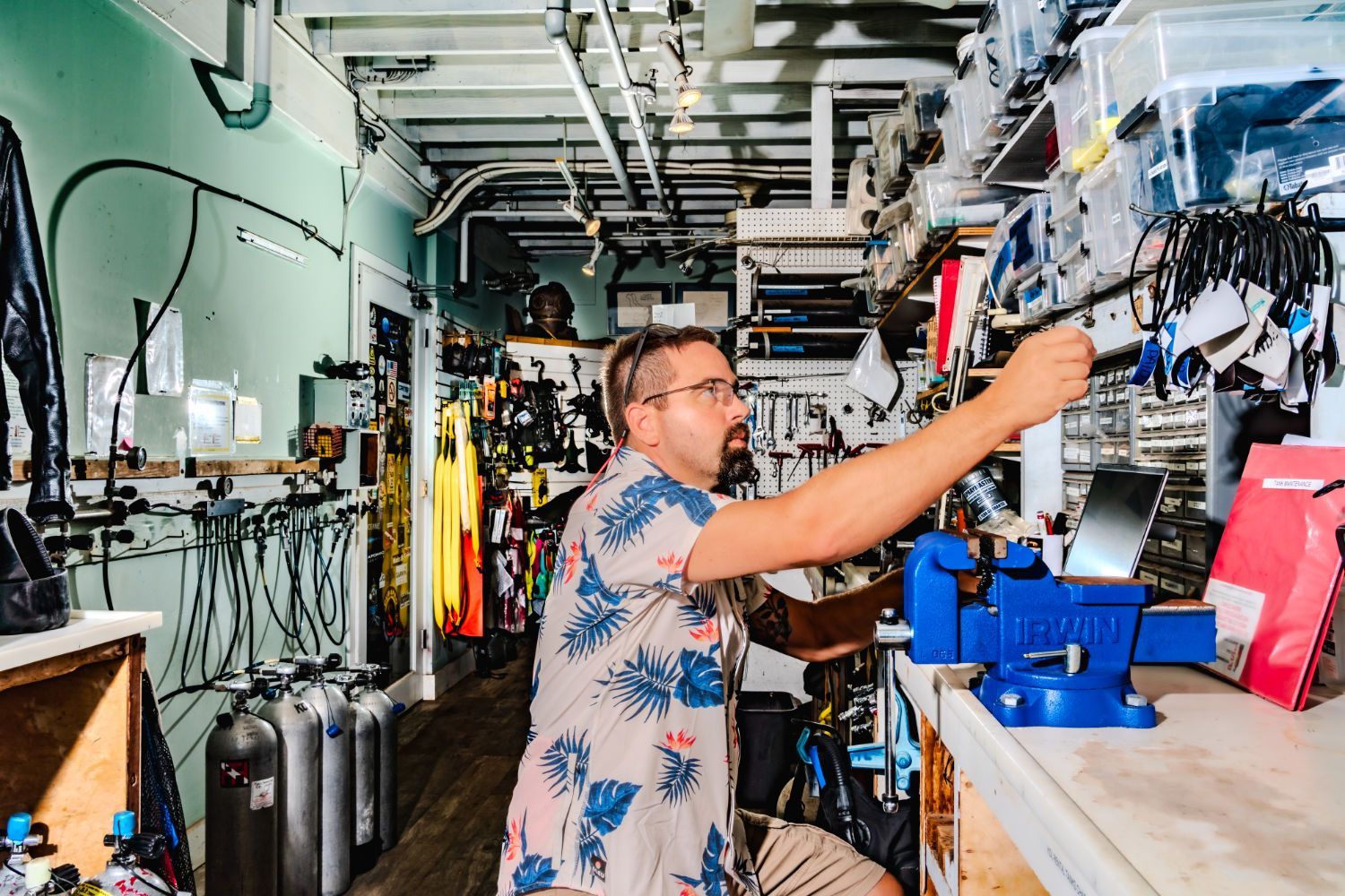 A man is working on a piece of scuba equipment in a workshop.
