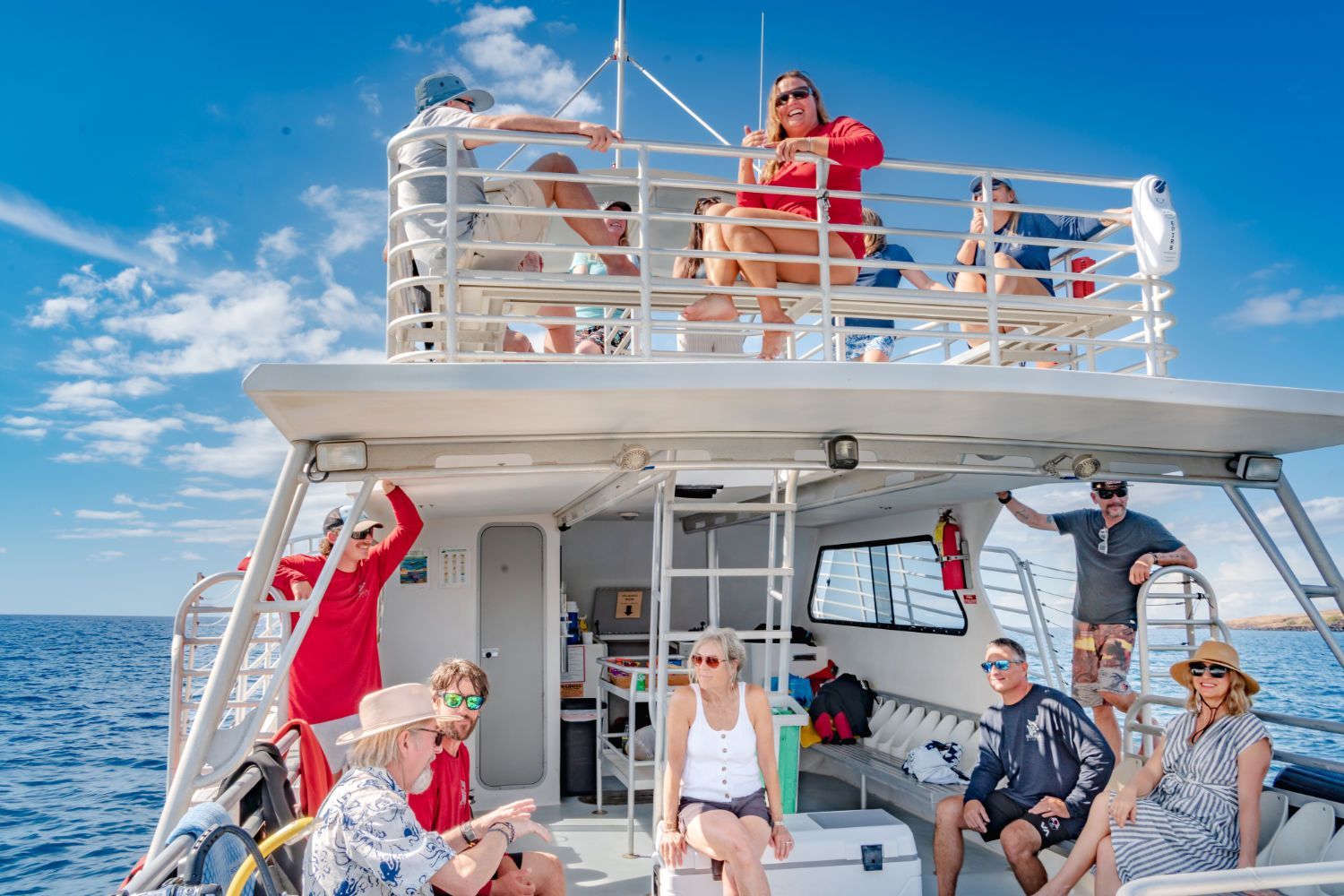A group of people are sitting on the back of a boat in the ocean.