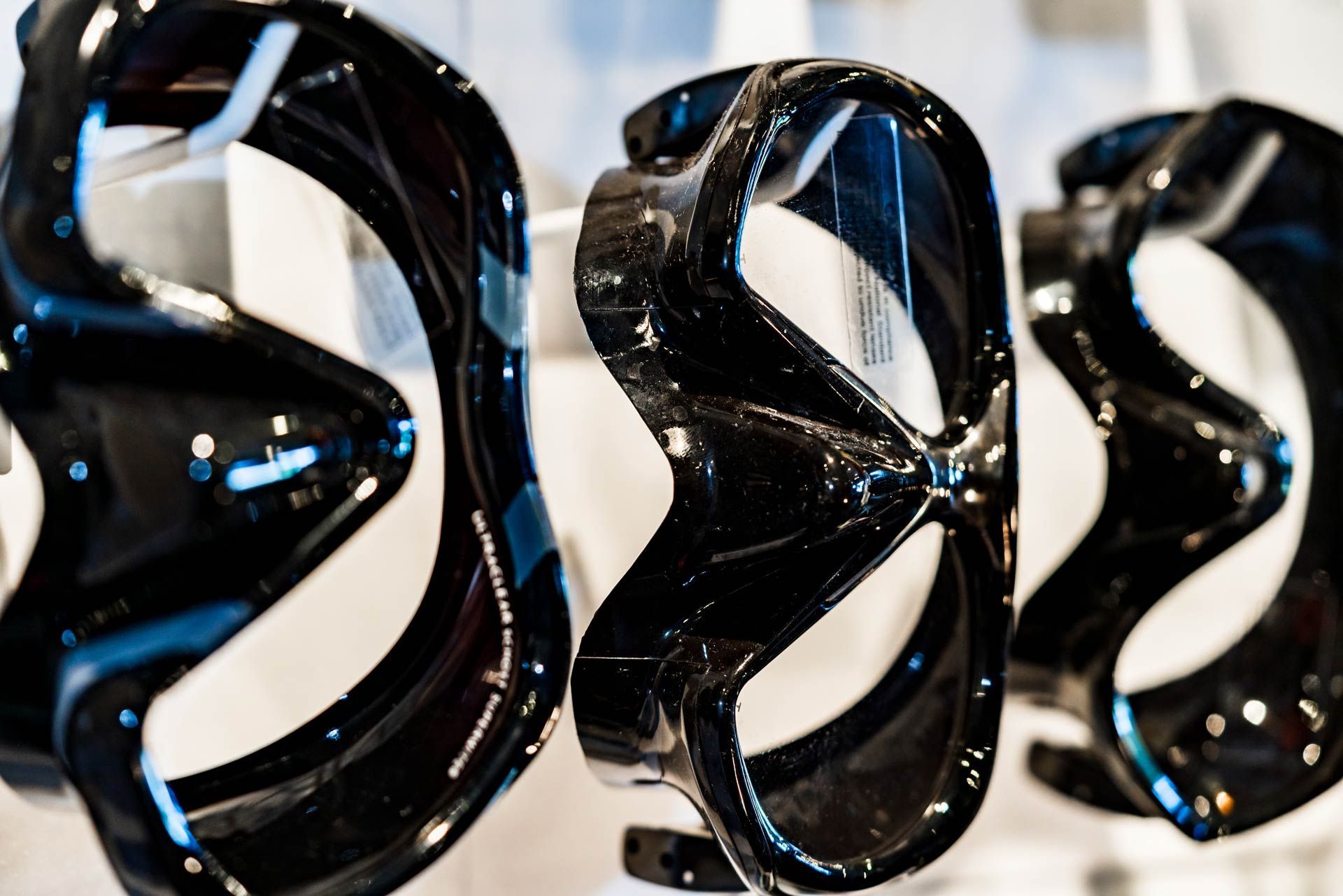 A row of black snorkel masks are hanging on a rack