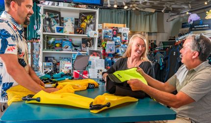 A group of people are sitting at a table in the dive shop.