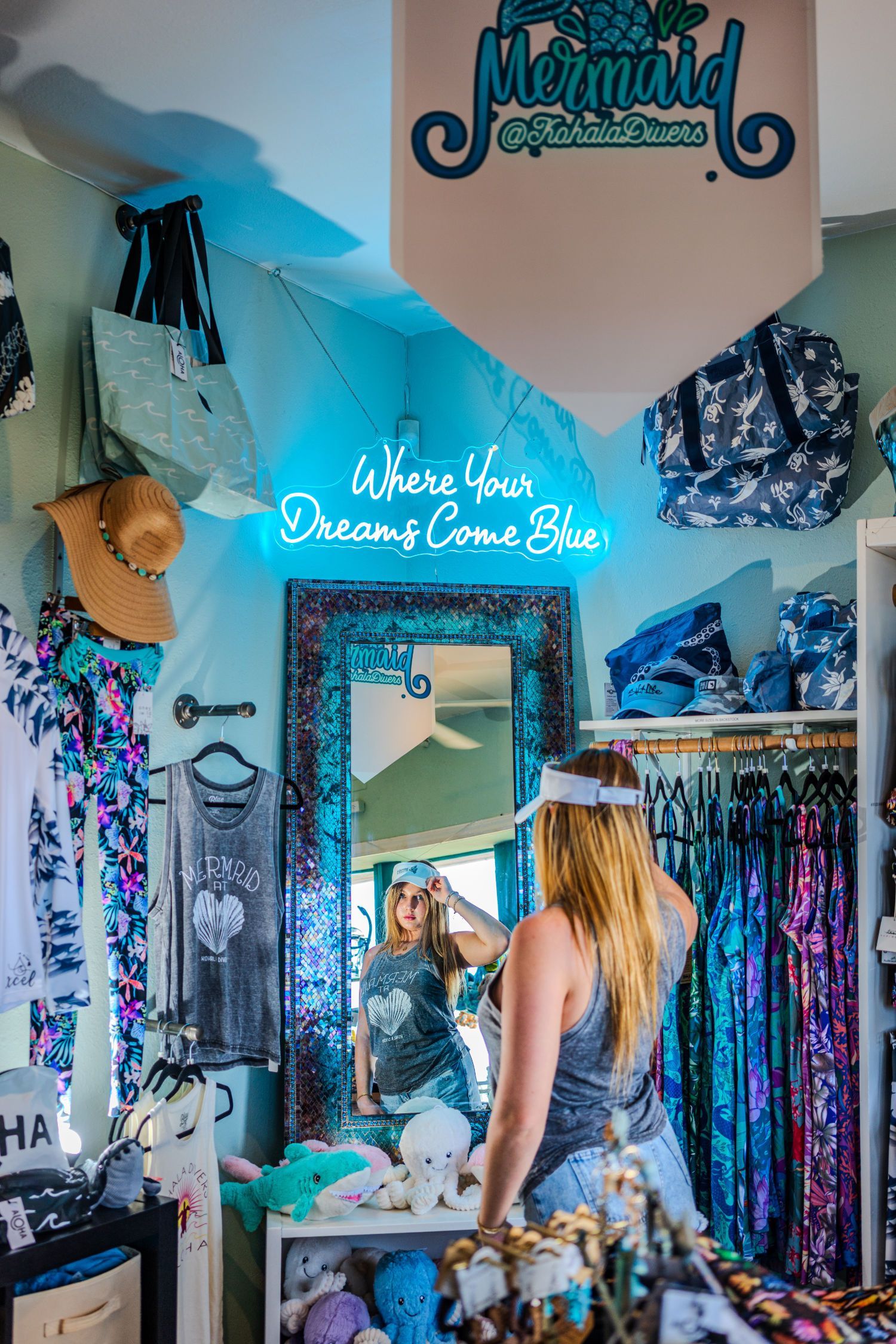 A woman is standing in front of a mirror in the dive shop.