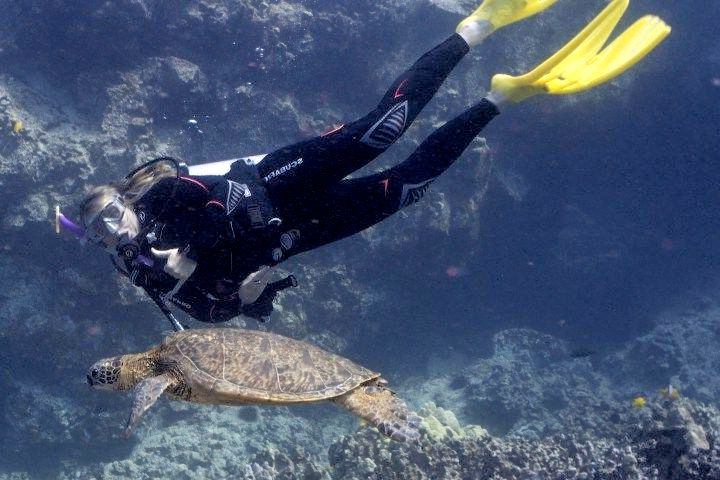 A man is helping a scuba diver out of the water.