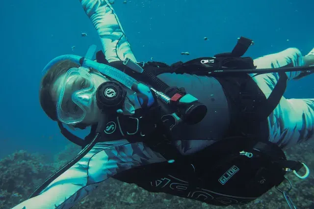 A person is swimming in the ocean with a scuba gear on.