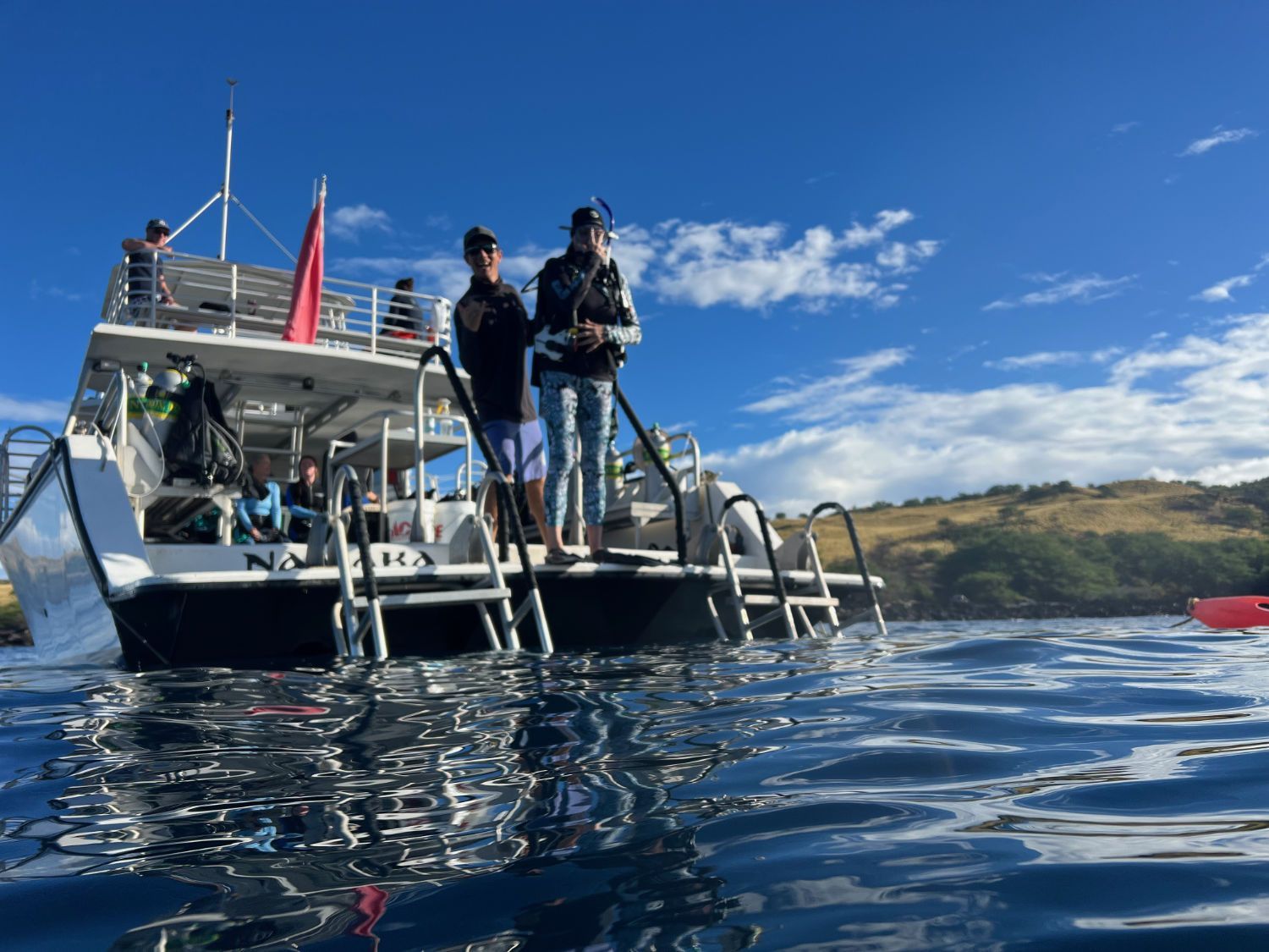 Two people are standing on a boat in the water.