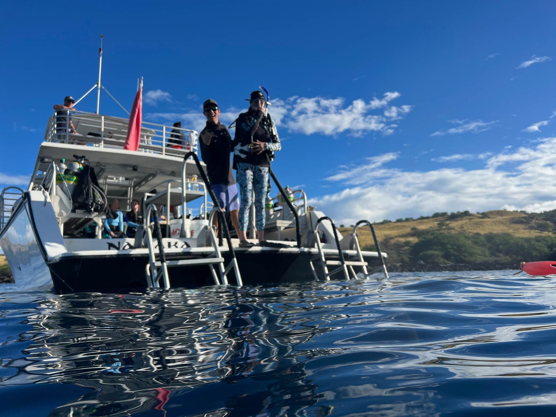 Two people are standing on a boat in the water.
