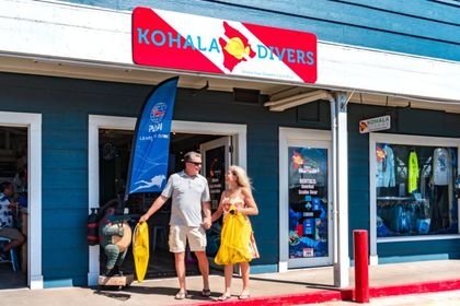 A man and a woman are walking in front of the dive shop.