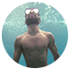 A shirtless man is swimming in the ocean wearing a mask and goggles.