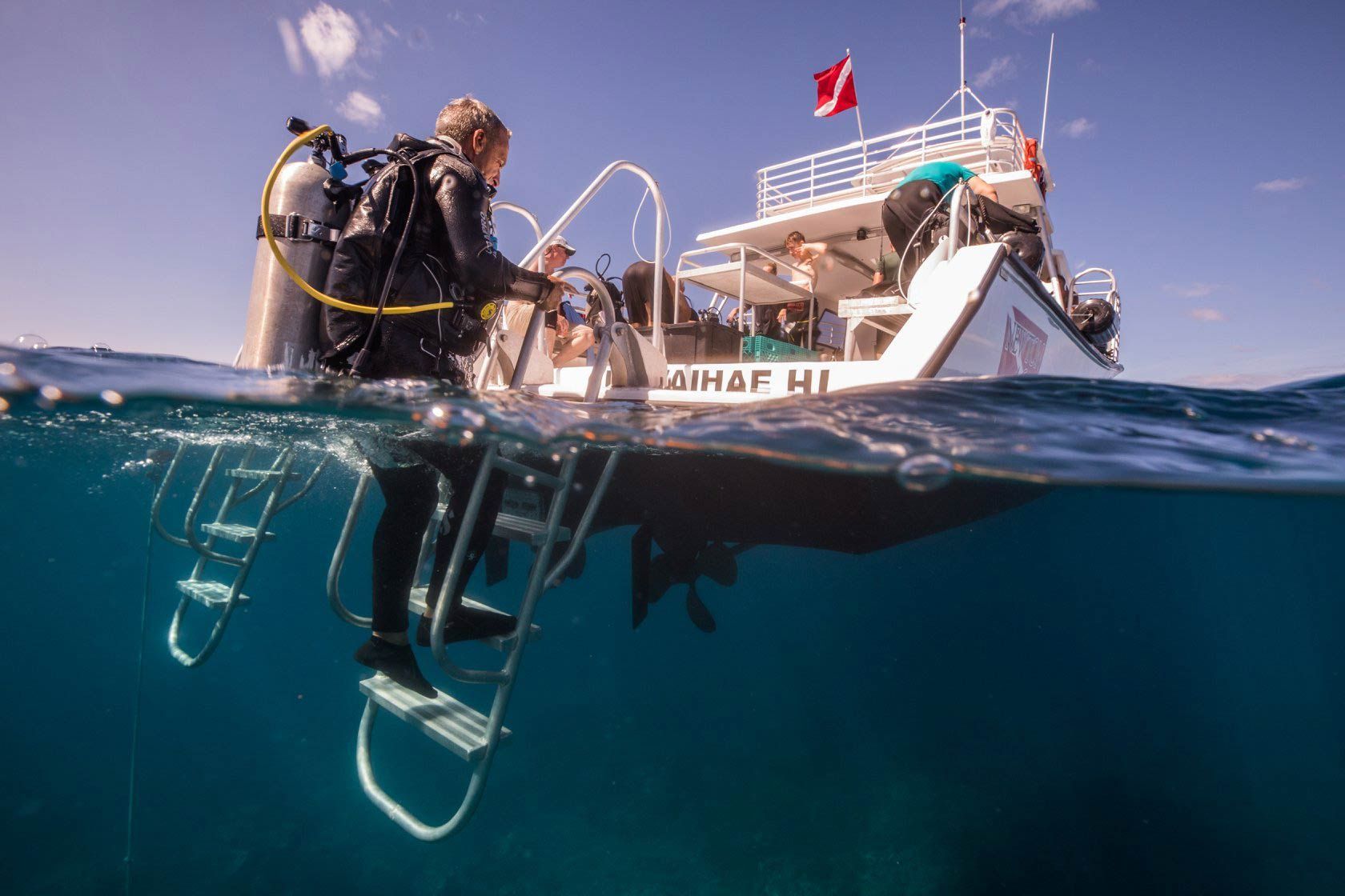 A scuba diver is standing next to a boat in the ocean.