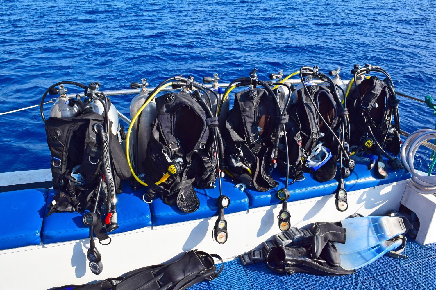A row of scuba diving equipment sitting on top of a boat in the ocean.