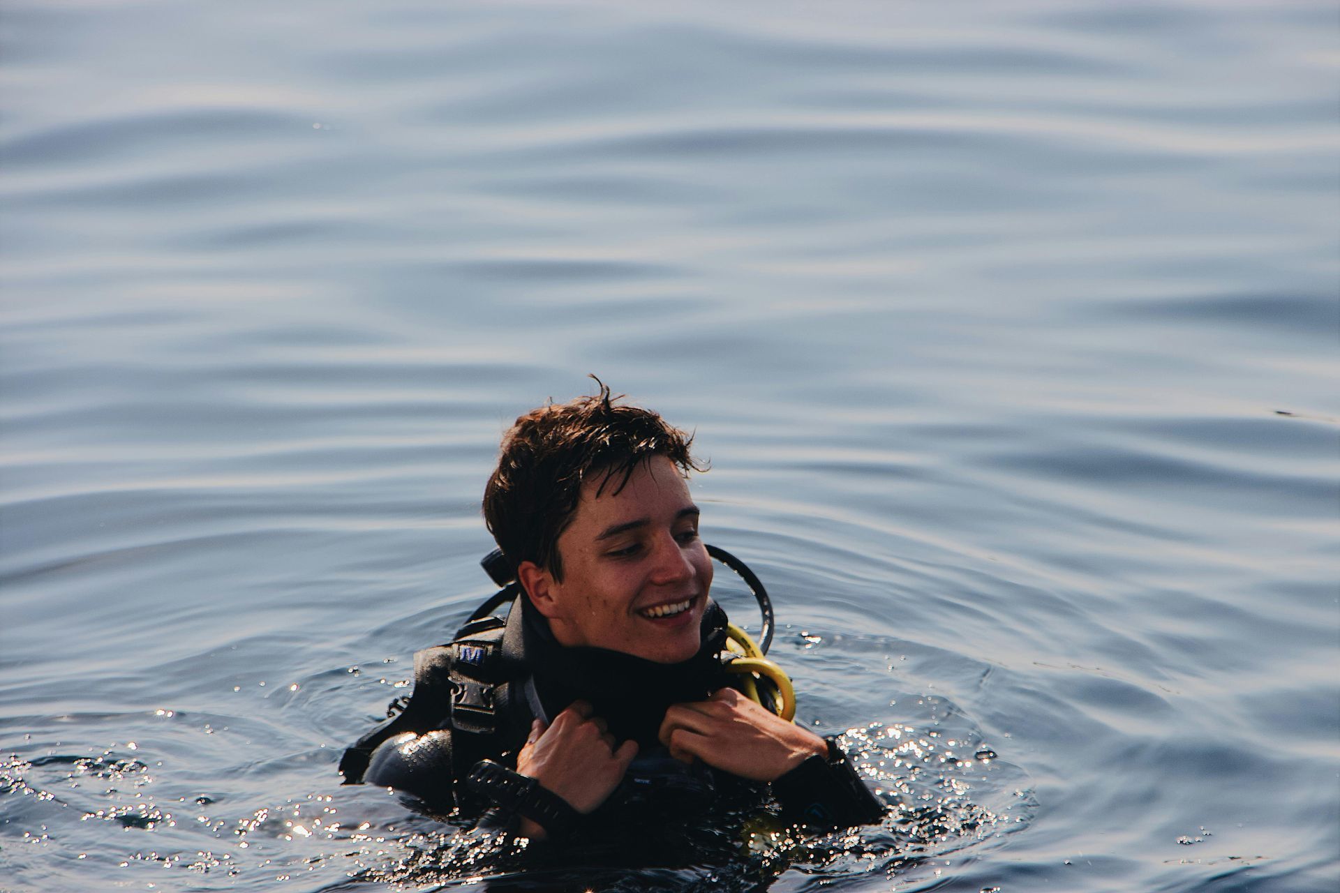 A man in a wet suit is swimming in the ocean.