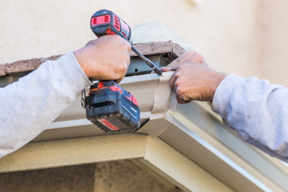 Professional using drill to install gutters