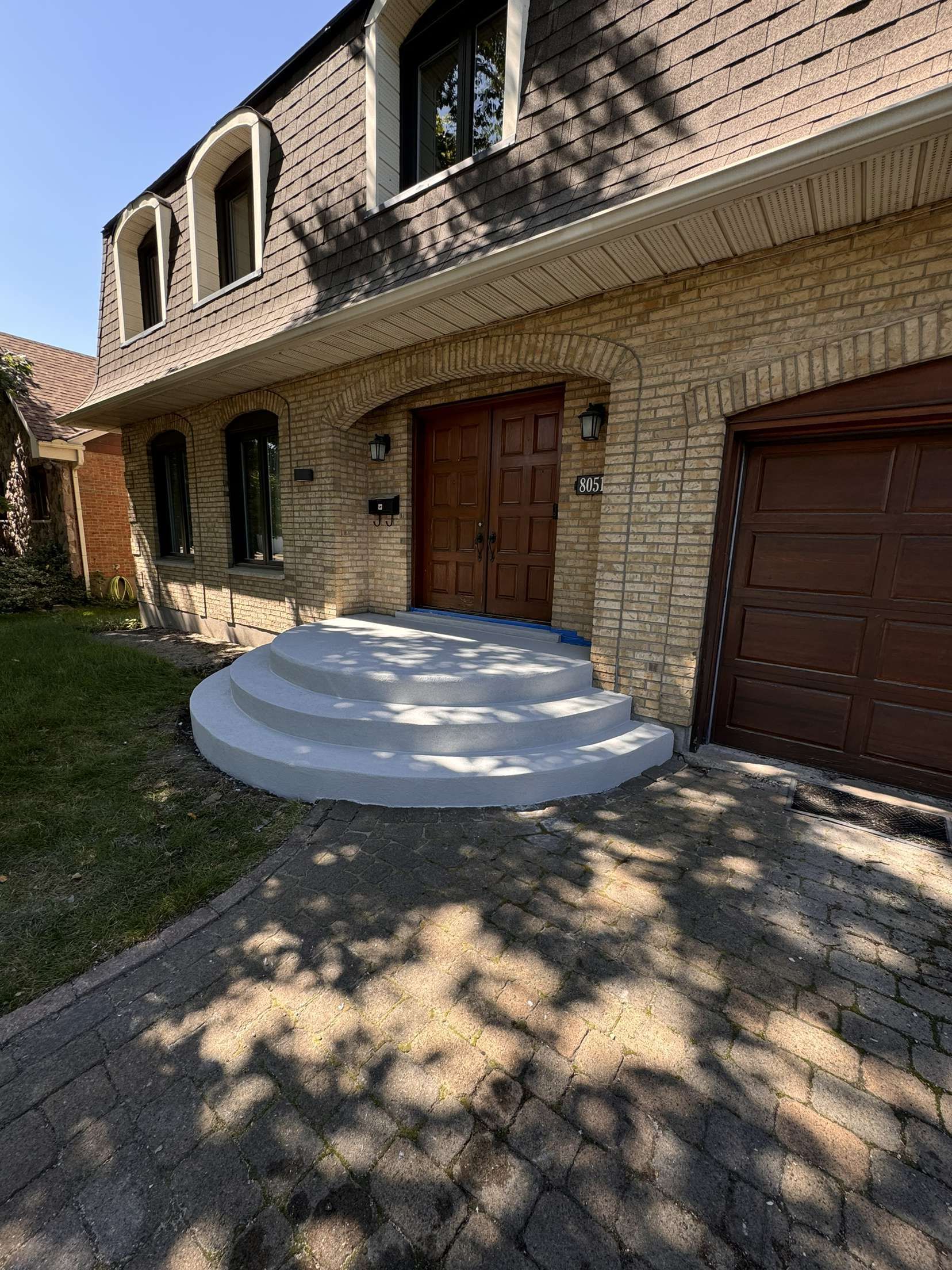 Une grande maison en brique avec un garage et des escaliers menant à la porte d'entrée.