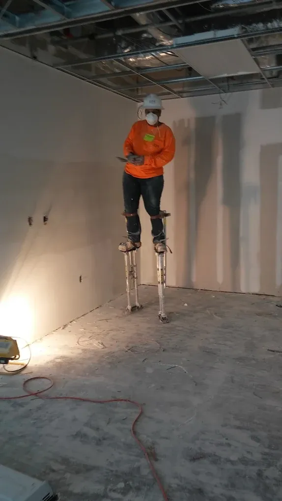 A man is standing on stilts in a room.