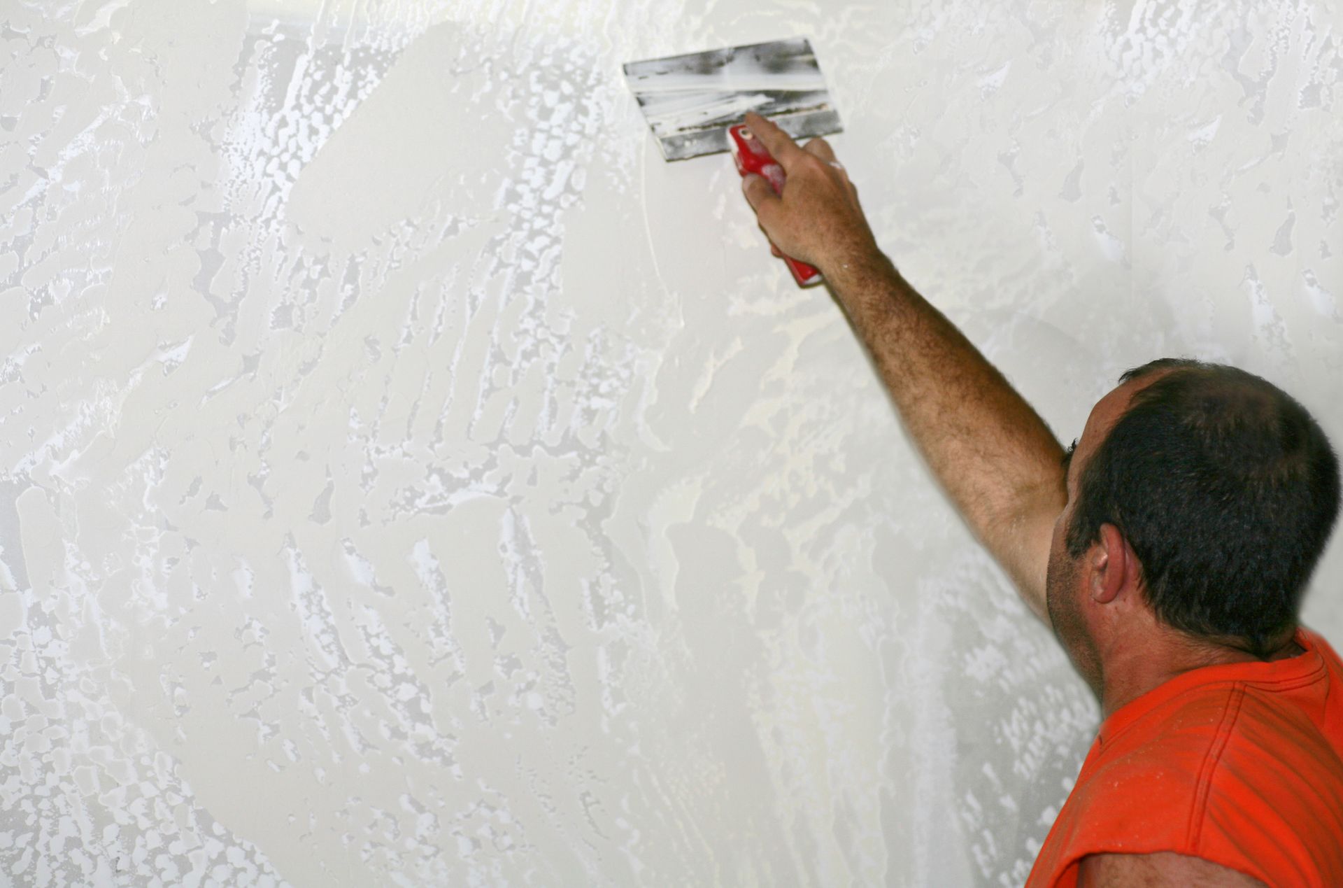 A man is plastering a wall with a spatula.