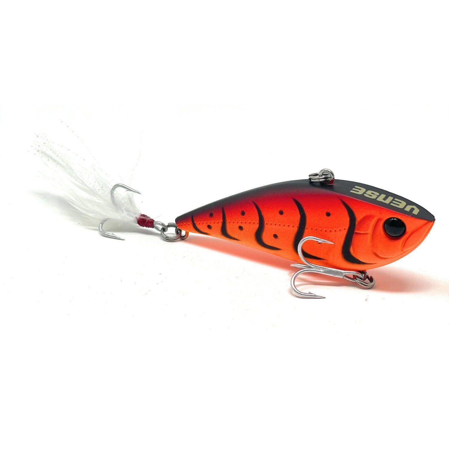 Señuelo de pesca rojo y negro con cola de plumas y anzuelos triples sobre fondo blanco.