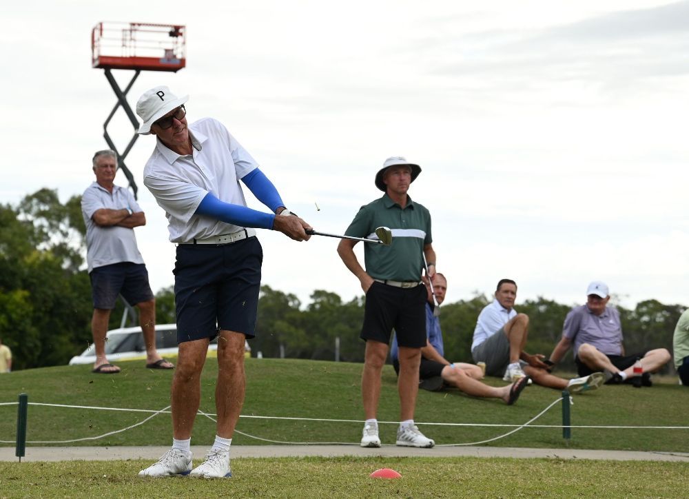 A man is swinging a golf club on a golf course while people watch — Rowes Bay Golf Club In Rowes Bay, QLD