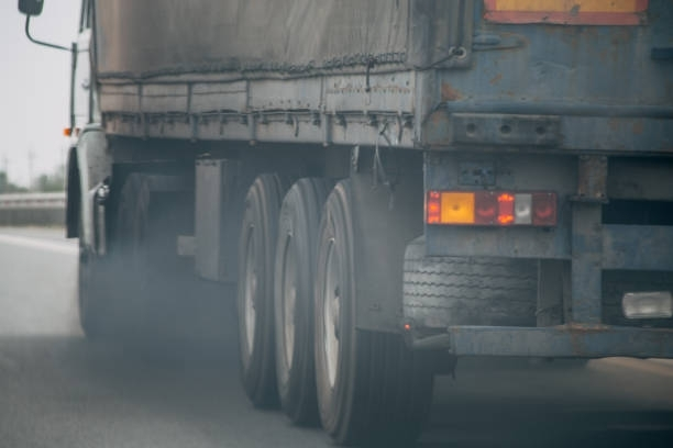Semi-truck on a highway, emitting dark exhaust from the rear tires.
