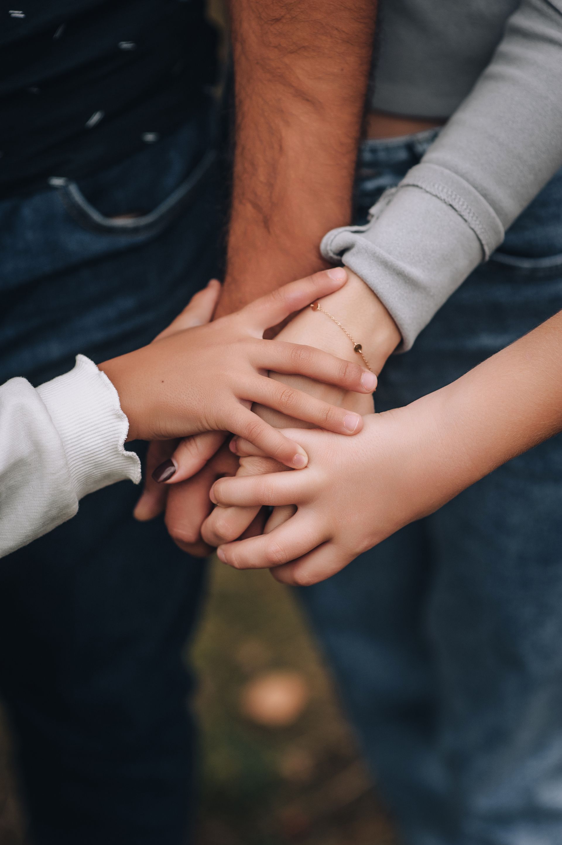 Three sets of hands are stacked together on top of one another, signaling unity and connection.