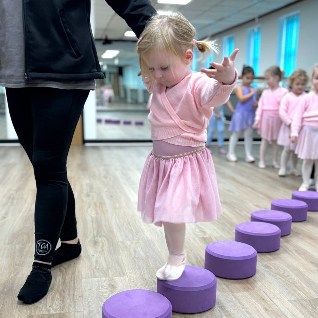 A group of women are practicing ballet in a dance studio