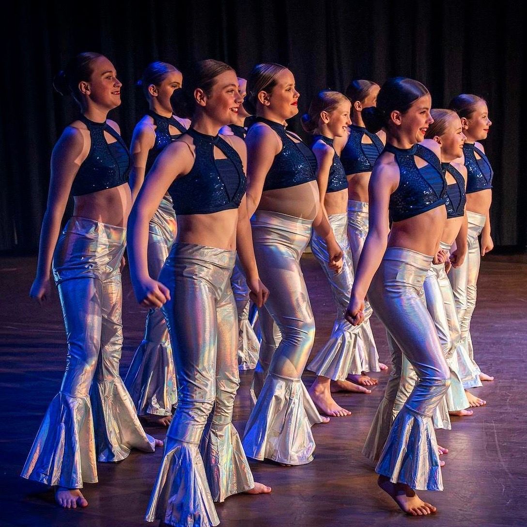 A group of women are posing for a picture on a stage