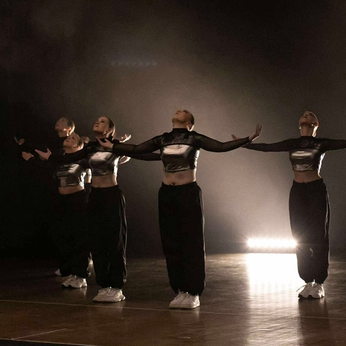 A group of people are dancing in a room with a clock on the wall