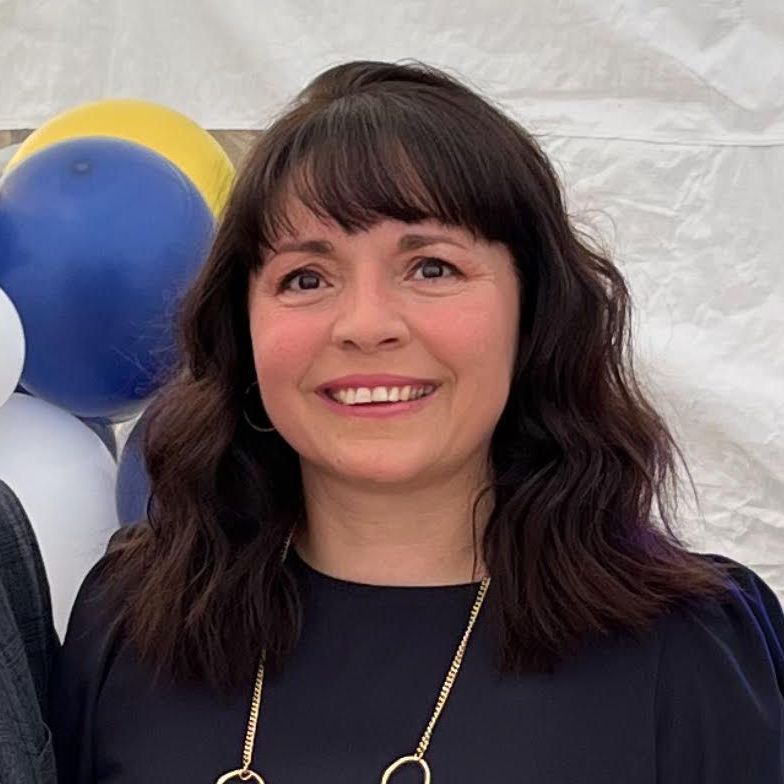 A woman is smiling while standing in front of balloons.