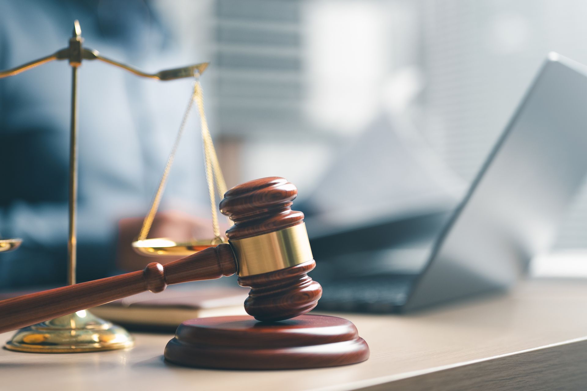 A gavel and justice scale are placed on a desk with a laptop, from a disability law attorney.