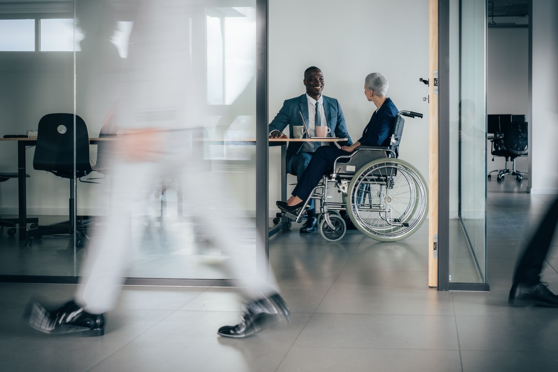 A disability law attorney meets a client in a wheelchair at a modern office.