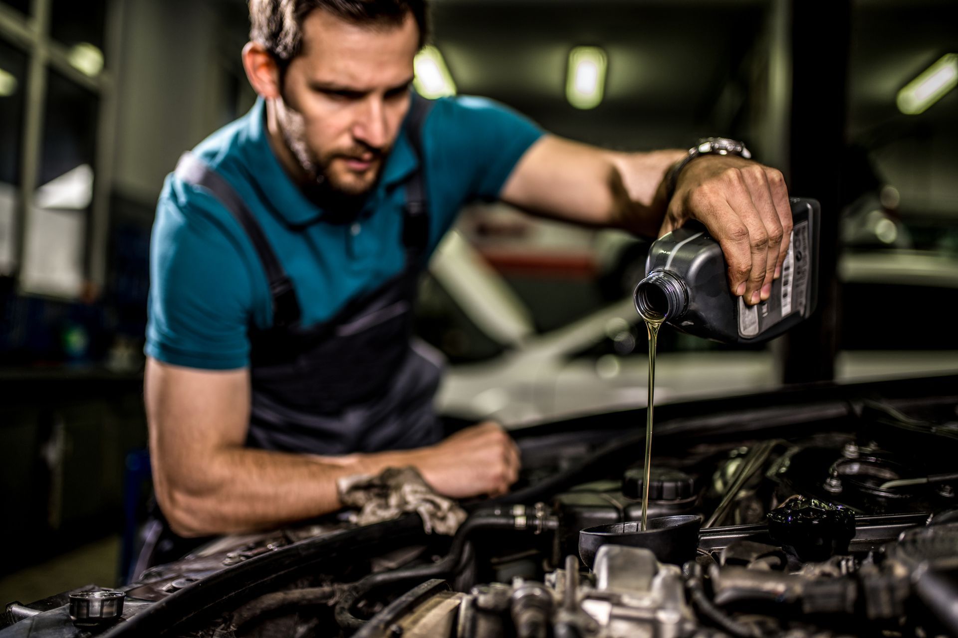 A man is pouring oil into a car engine.