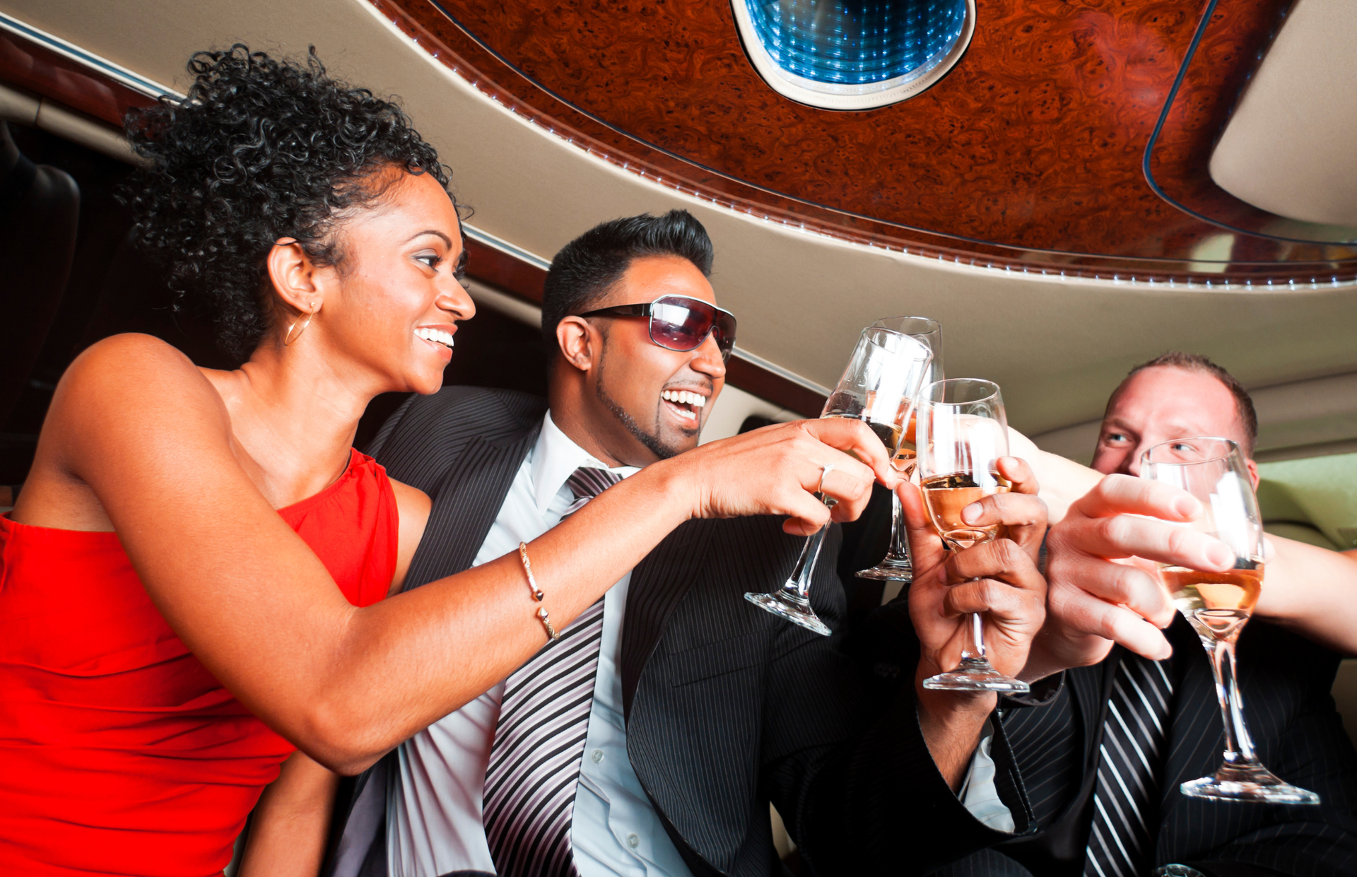 People in formal wear toasting drinks in a dimly lit lounge, smiling and laughing