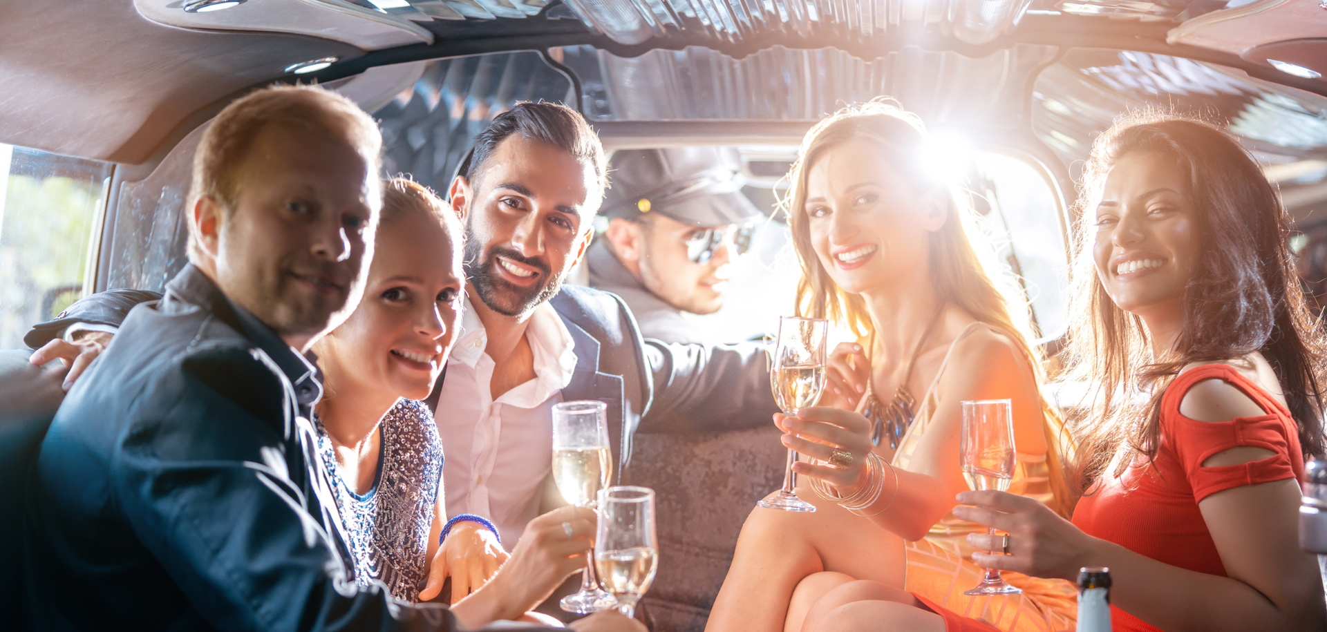Group of friends smiling and toasting drinks in a warmly lit bar booth